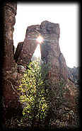 Pillars of volcanic rock frame the setting sun along a trail in the Superstition Mtns, near Gold Canyon, Arizona.